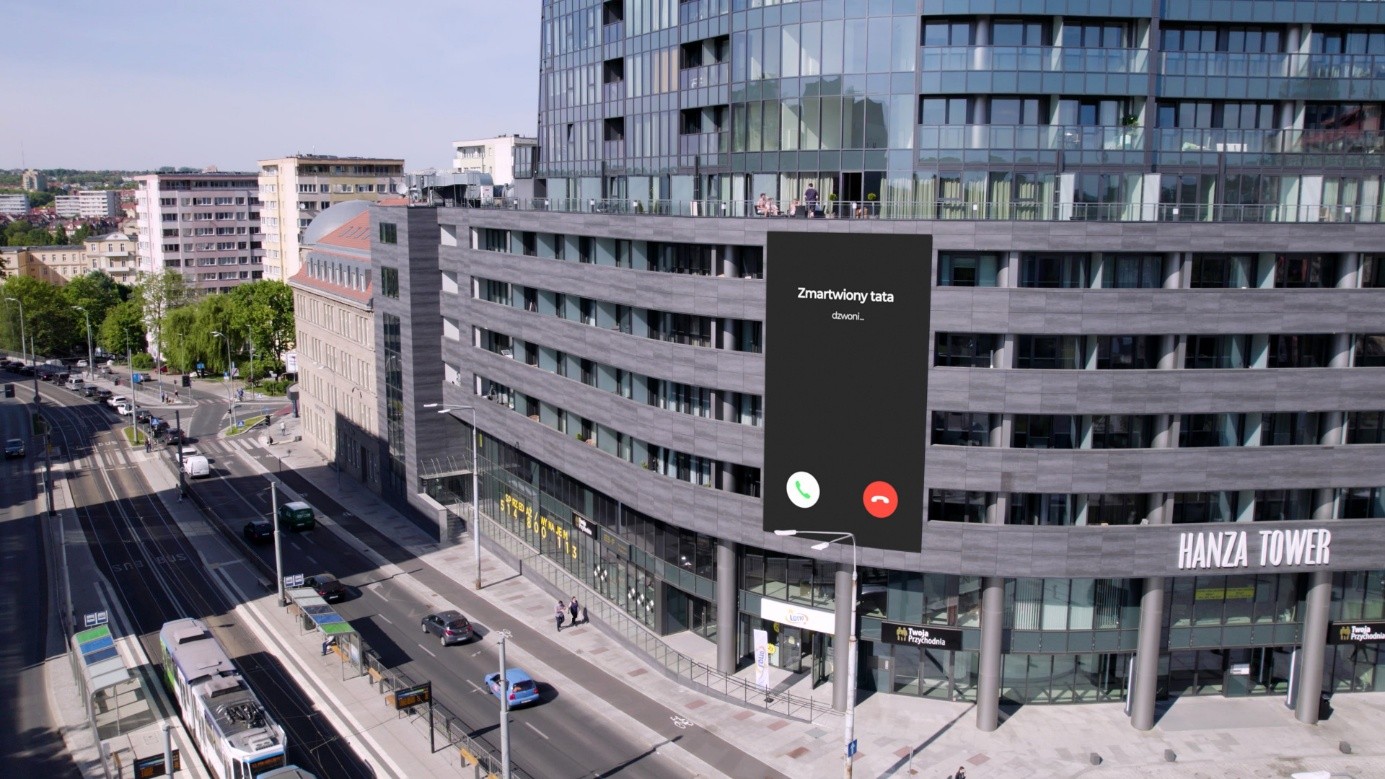 Na budynku ekran telefonu, na którym wyświetla się napis: Zmartwiony tata dzwoni.