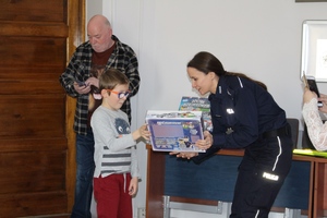 Policjantka wręcza dziewczynce grę.