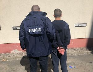Policjant prowadzi jednego z podejrzanych.