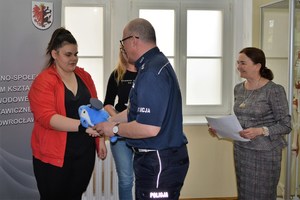 Naczelnik WRD wręcza uczennicom maskotki policyjne za rozwiązanie quizu.