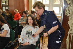 Policjantka wręcza uczniom magnesy o Krajowej Mapie Zagrożeń Bezpieczeństwa.