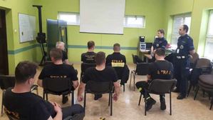 Policjanci podczas szkolenia strażaków udzielają im wskazówek.