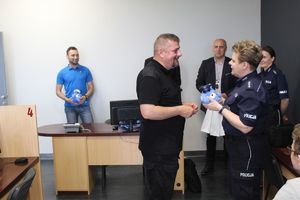 Uczestnik spotkania odbiera od policjantki maskotkę.