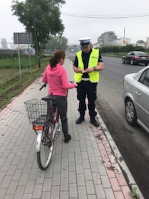 Policjant rozmawia z rowerzystką o przepisach.