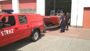 Strażak prezentuje łódź motorową przygotowaną do działań.