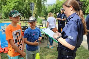 Policjantka pyta dzieci o zasady przebywania w lesie.