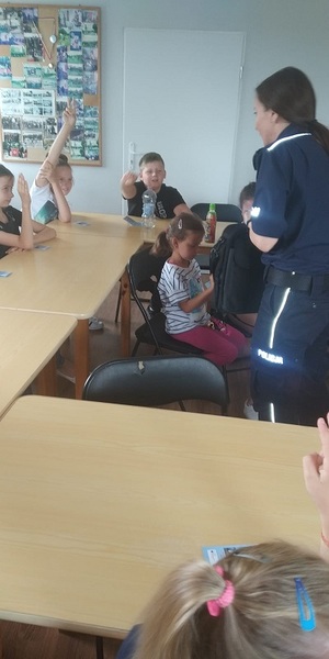 policjantka podchodzi do zgłaszającego się młodego chłopca, uczestnika półkolonii