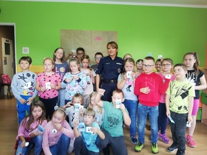policjantka wraz ze stojącymi w szeregach dziećmi pozują do zdjęcia