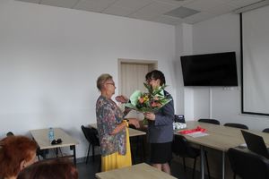 Seniorka wręcza kwiaty.