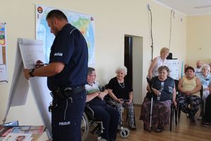 Policjant prowadzi warsztaty, pisząc na tablicy elementy wizerunku człowieka.