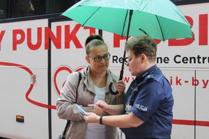 Policjantka pokazuje mieszkance miasta magnesy o KMZB.