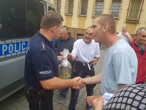 Policjant wyposaża osoby w ulotki.