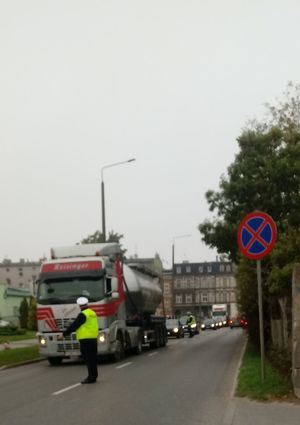 Policjant zatrzymuje samochód ciężarowy do kontroli.