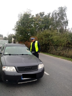 Policjant WRD podaje kierowcy urządzenie do badania stanu trzeźwości.