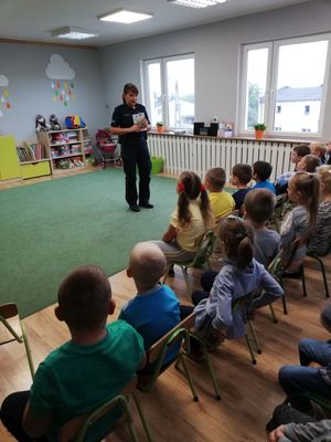 Policjantka omawia książeczkę edukacyjną.