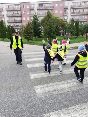 Policjantka przeprowadza dzieci po pasach.