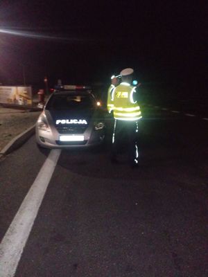 Policjanci spoglądają w stronę nadjeżdżających samochodów.