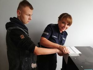Policjantka demonstruje ściąganie odbitek palców.