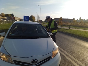 Policjant sprawdza trzeźwość jadącego pojazdem do nauki jazdy.