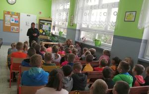 Klasy zebrane na korytarzu uczestniczą w pogadance z policjantką.