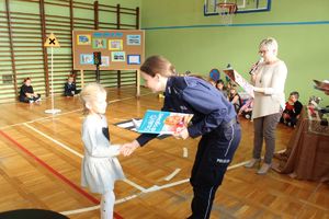 Policjantka wręcza dziecku książkę.