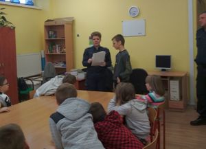 Policjantka z uczniem zadają dzieciom zagadki.