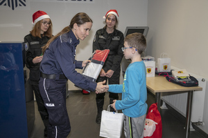 Policjantka podaje dziecku paczkę z upominkami