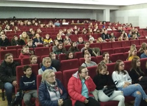 Widownia teatru, na której siedzą wolontariusze-uczestnicy spotkania w różnym wieku.