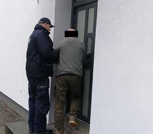 Policjant doprowadza zatrzymanego