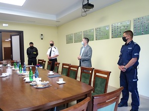 Sala w urzędzie miasta. Od lewej stoją strażak ochotniczej straży pożarnej w mundurze, komendant państwowej straży pożarnej w mundurze, zastępca burmistrza Kruszwicy, I Zastępca Komendanta Wojewódzkiego Policji w mundurze. Wszyscy w odstępach od siebie i z maseczkami na twarzach.