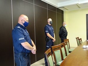 Od lewej stoją umundurowani Komendant Powiatowy Policji w Inowrocławiu, policjant kruszwickiego komisariatu, strażak ochotnik. Wszyscy w mundurach i z zachowanymi odstępami i z maseczkami na twarzach.