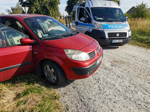 na polnej drodze stoi oznakowany radiowóz i kontrolowane auto osobowe