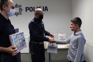 Policjant gratuluje chłopcu udziału w konkursie