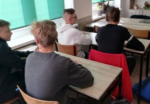 Uczniowie siedzą w ławkach na lekcji z policjantką