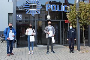 Policjantka, nauczyciel i dwójka uczniów stoi na tle budynku inowrocławskiej komendy