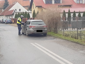 Policjant stoi przy pojeździe i kontroluje kierowcę