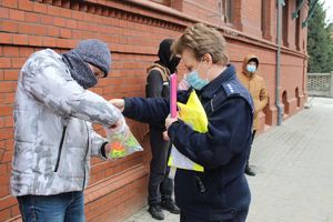 Mężczyzna ma zakładaną na rękę taśmę odblaskową przez policjantkę