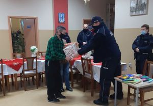 Policjanci wręczają seniorom paczki