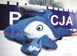 Maskotka policyjna Polfin na tle napisu Policja