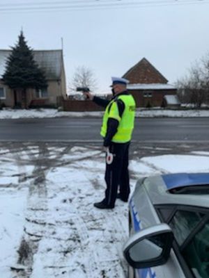 Policjant stoi na drodze z miernikiem prędkości w ręku