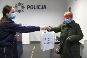 Policjantka przekazuje kobiecie upominkowa paczkę