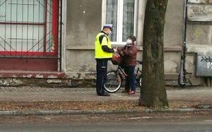 Cyklistka otrzymuje taśmę odblaskową od policjanta ruchu drogowego