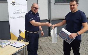 W imieniu żony mąż odbiera od policjanta upminek