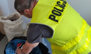 Policjant przelicza ujawnione papierosy
