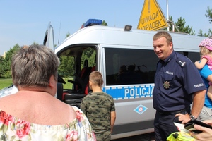Policjant zaprasza dzieci do środka radiowozu