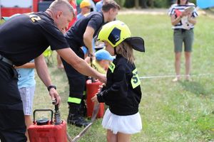 Strażak ubiera dziecko w strażacki mundur