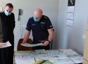 Policjant i ksiądz ogląda rysunki dzieci