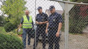 Policjanci stoją przed ogrodzeniem domu