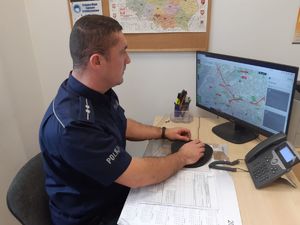 Policjant siedzi przy biurku i komputerze