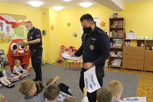 Policjanci wręczają dzieciom upominki